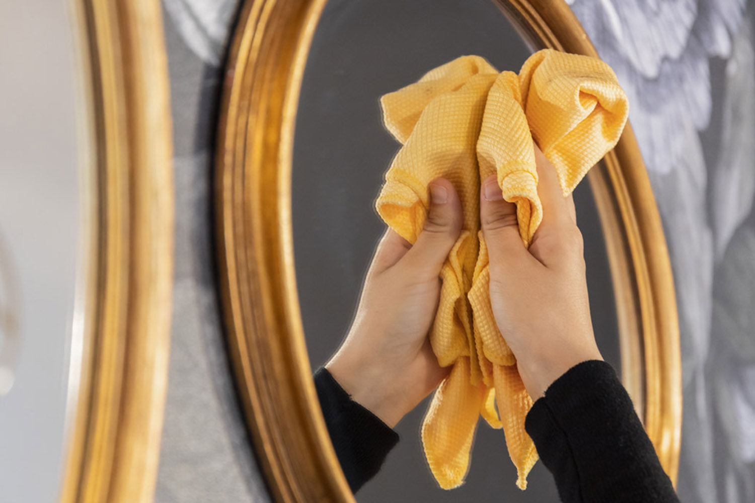 mano con panno arancione in microfibra pulisce specchio con bordo d'orato
